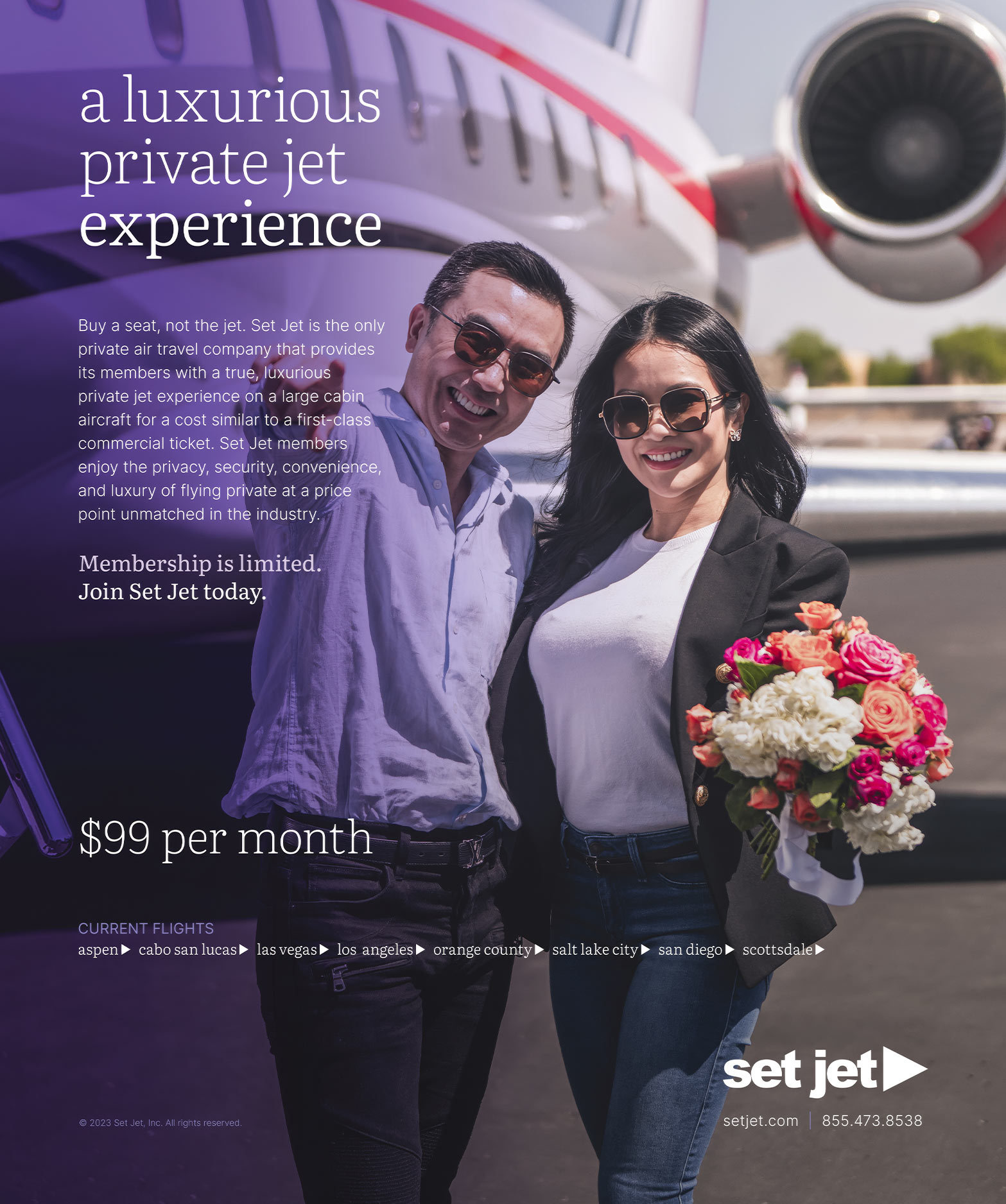 A smiling couple standing by a private jet; the woman holds flowers while the man points at the camera.